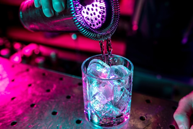 Gros plan sur un cocktail alcoolisé, une boisson, une boisson, un verre plein de glace dans un néon multicolore