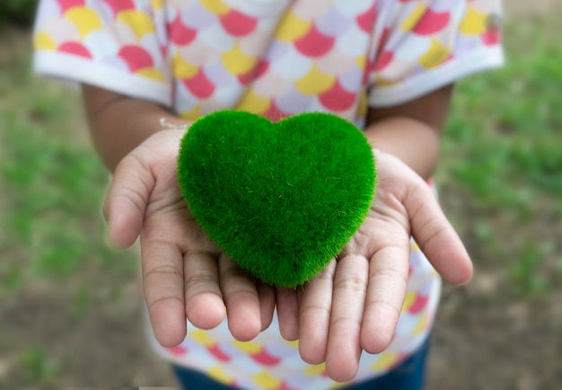 Photo gros plan d'un cœur vert sur la petite main de l'enfant