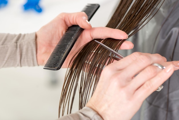 Gros plan d'un coiffeur coupant les cheveux d'une femme.