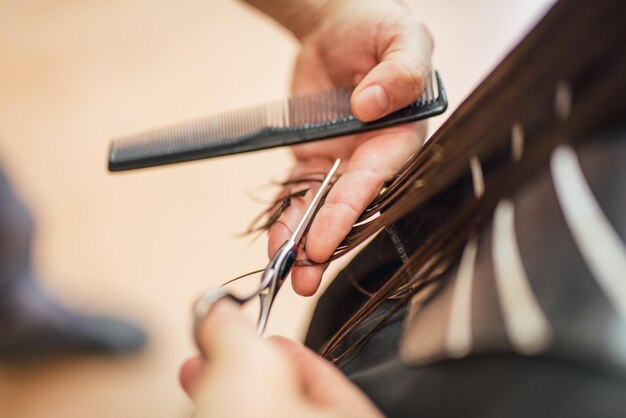 Gros plan d'un coiffeur homme coupant les cheveux d'une femme.