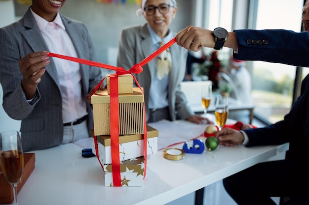 Photo gros plan de collègues ouvrant des cadeaux lors d'une fête de noël au bureau