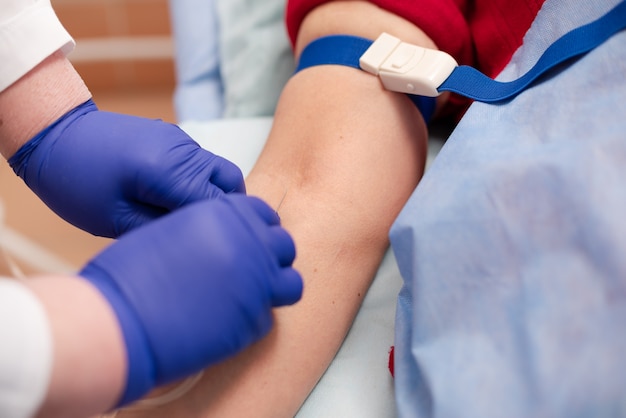 Photo gros plan sur le concept de médecine. une infirmière médicale avec des gants en latex bleu introduit un cathéter dans une veine du patient pour une perfusion de chimiothérapie ou un autre médicament liquide contre le cancer