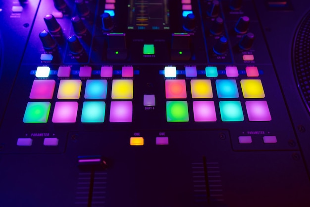 Gros plan sur une console de mixage DJ dans la lumière du parti