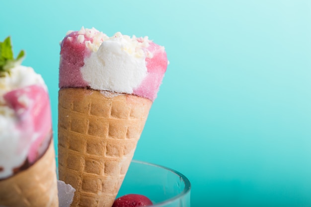 Gros Plan De Cornet De Crème Glacée. Cuillère à Glace Rose En Cône De Gaufre Sur Fond Bleu. Saveur Fraise Ou Framboise Dessert Sucré Décoré De Paillettes Colorées, Gros Plan