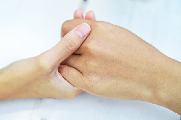 Gros plan d&#39;un couple ou un ami tenant par la main sur la table en bois