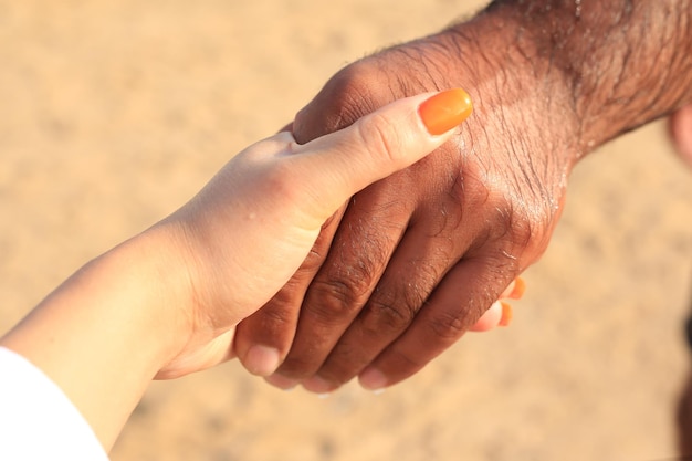 Gros plan d'un couple amoureux se tenant la main sur la plage de la mer