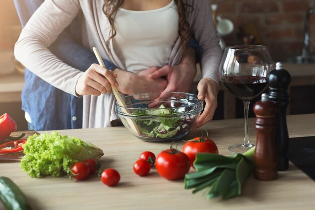 Gros plan d'un couple cuisinant des aliments sains ensemble dans leur cuisine loft à la maison. Préparation de la salade de légumes.