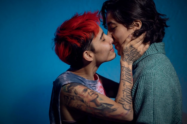 Gros plan d'un couple de lesbiennes sur le point de s'embrasser sur un fond bleu