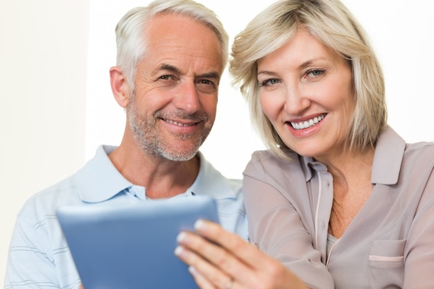 Gros plan d&#39;un couple mature souriant à l&#39;aide de tablette numérique