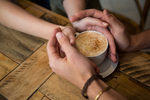 Gros plan, de, couple tenant mains, et, tasse café, dans, cafétéria