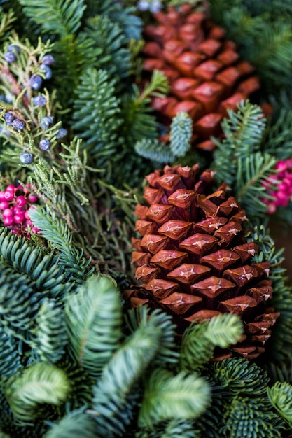 Gros plan sur une couronne de Noël décorée de pommes de pin et de baies.