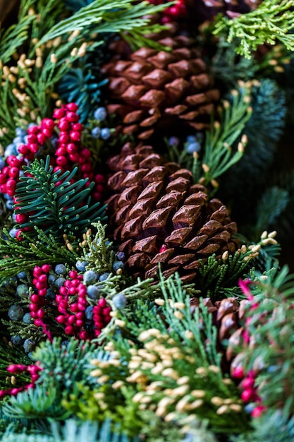 Gros plan sur une couronne de Noël décorée de pommes de pin et de baies.