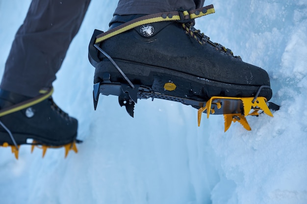 Gros plan des crampons sur ses pieds grimpeur sur glace, grimpeur sur un hiver gelé