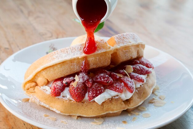 Gros plan de crème glacée à la vanille avec gaufre et fraise fraîche sur fond de table en bois