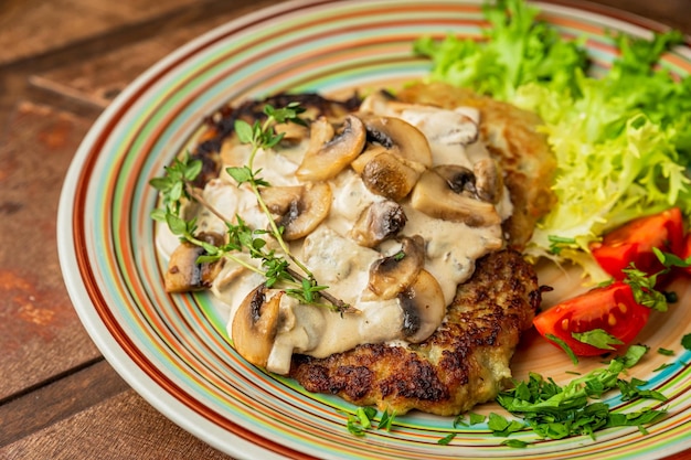 Un gros plan de crêpes de pommes de terre avec sauce à la crème de champignons, laitue, tomates cerises et thym, table en bois