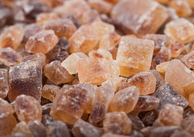 Gros plan de cubes de sucre caramélisés naturels sur blanc.