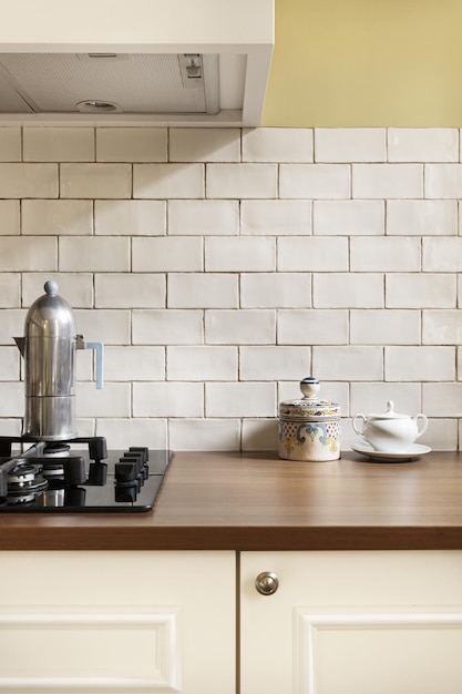 Un gros plan d'une cuisine avec une plaque de cuisson au gaz de petits carreaux blancs et un plan de travail en bois