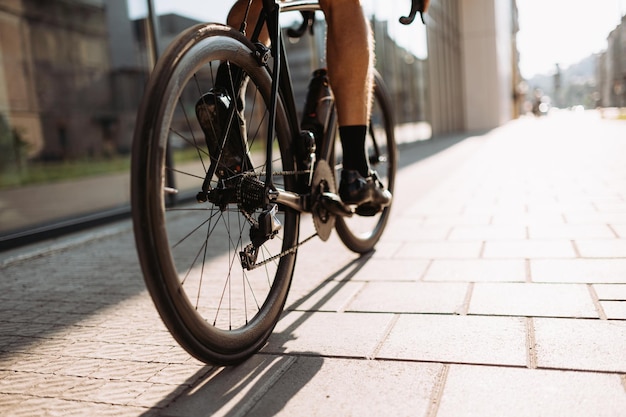 Gros plan d'un cycliste masculin en vêtements de sport et baskets à vélo noir pendant la matinée dans la zone urbaine Activité à l'extérieur d'un homme en bonne santé et en forme