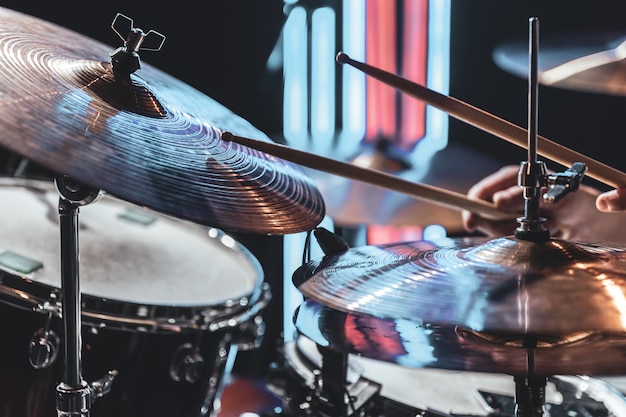 Photo gros plan sur des cymbales de batterie alors que le batteur joue avec un bel éclairage sur un arrière-plan flou.