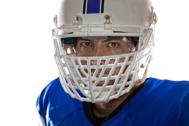 Gros plan dans les yeux d'un joueur de football avec un uniforme bleu sur un mur blanc