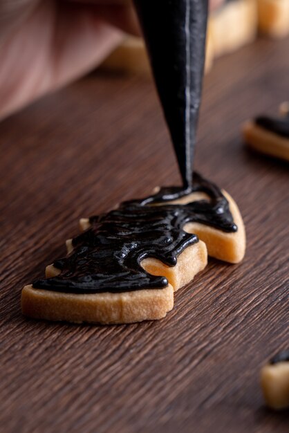 Gros plan de la décoration de mignons biscuits de pain d'épice de chauve-souris Halloween avec sac de garniture de crème glacée glaçage.