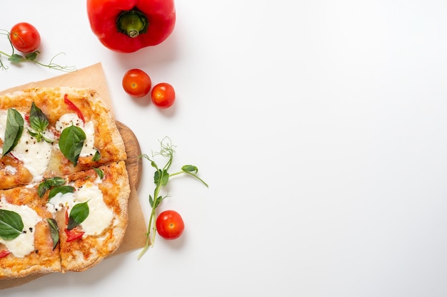 Gros plan d'une délicieuse pizza romaine avec des légumes sur une planche de bois fond blanc autour de tomates rouges mûres et de micro-verts se trouvent à proximité Cuisine italienne traditionnelle Vue de dessus espace de copie plat