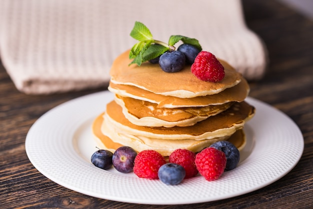 Gros plan de délicieuses crêpes aux myrtilles et framboises fraîches.