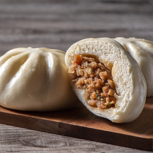 Photo gros plan de délicieux baozi frais, pain de viande cuit à la vapeur chinois est prêt à manger sur une assiette de service et un cuiseur à vapeur, gros plan, copiez le concept de conception de produit d'espace