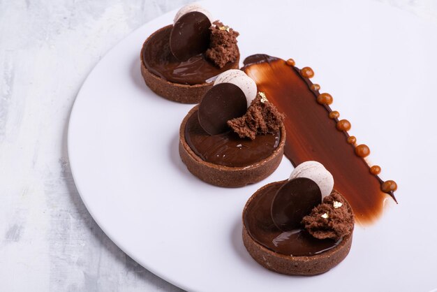 Gros plan d'un délicieux dessert au chocolat avec macaron servi sur une assiette blanche