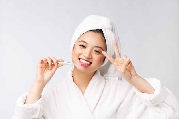 Gros plan des dents de brosse femme sourire. idéal pour le concept de soins dentaires de santé, isolé sur mur blanc. asiatique.