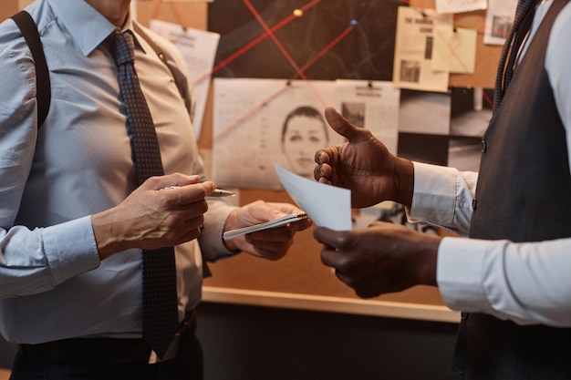 Photo gros plan sur deux détectives masculins méconnaissables discutant de l'affaire au cours de l'enquête