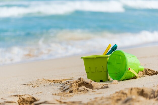 Gros plan de deux jouets de sable pour enfants verts avec des seaux et des pelles sur une plage à Hawaii