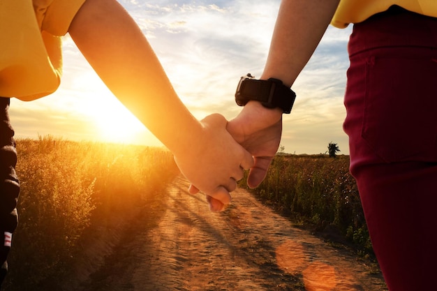 Gros plan de deux sœurs se tenant la main en marchant à l'heure du lever du soleil