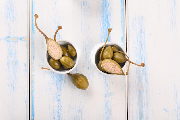 Un gros plan de deux tasses blanches avec des olives sur une table en bois bleue.