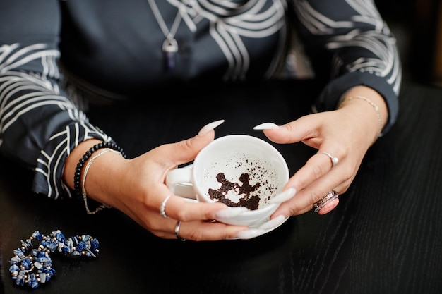 Gros plan sur une diseuse de bonne aventure tenant une tasse de café et racontant le destin par des motifs dans l'espace de copie de séance