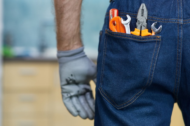 Gros plan de divers outils à main de plomberie dans la poche arrière du jean de l'homme