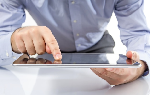 Gros plan des doigts de l'homme touchant l'écran sur une tablette électronique numérique moderne