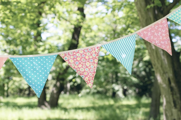 Gros plan de drapeaux banderoles suspendus parmi les arbres Fête de jardin d'été Décoration de mariage d'anniversaire en plein air Concept de festa junina au milieu de l'été Mise au point sélective Arrière-plan flou naturel