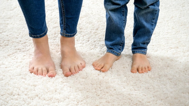 Photo gros plan d'une drôle de mère pieds nus avec son fils dansant sur un tapis blanc doux