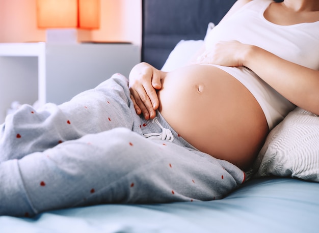 Gros plan du beau ventre de femme enceinte de femme allongée dans son lit concept de grossesse maternité