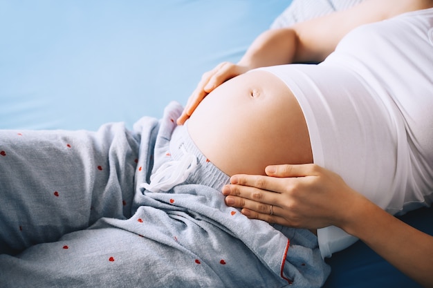 Gros plan du beau ventre de femme enceinte de femme allongée dans son lit concept de grossesse maternité