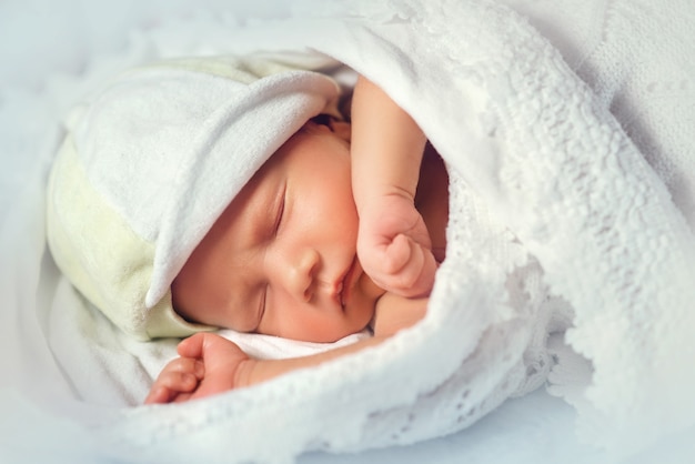 Gros plan du bébé nouveau-né mignon faisant la sieste sur des feuilles de dentelle blanche.