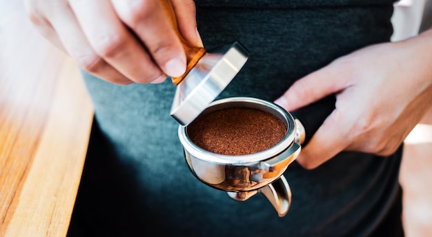 Gros plan du café Barista à la main faisant du café avec des presses manuelles du café moulu à l'aide d'un tamper