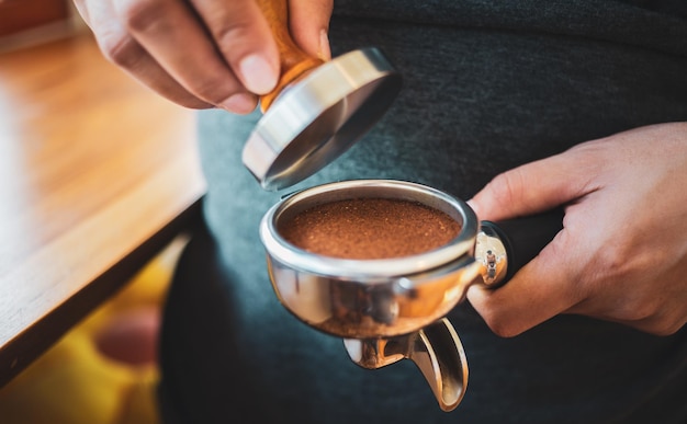 Gros plan du café Barista à la main faisant du café avec des presses manuelles du café moulu à l'aide d'un tamper