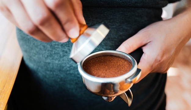 Gros plan du café Barista à la main faisant du café avec des presses manuelles du café moulu à l'aide d'un tamper