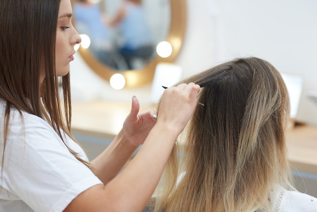 Gros plan du coiffeur en train de peigner les cheveux du client dans un salon de beauté