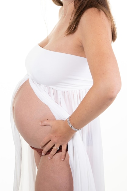 Gros plan du corps de la femme enceinte vue latérale tenant le ventre en chemise blanche