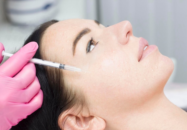 Le gros plan du cosmétologue fait la procédure d'injections faciales rajeunissantes pour resserrer la peau du visage de la femme dans une clinique de beauté Procédure de bio-revitalisation