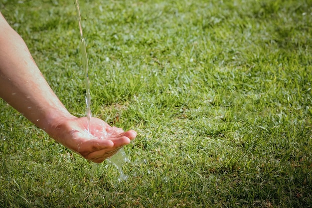 Gros plan du débit d'eau à la main des femmes pour le concept de la nature sur le fond du jardin