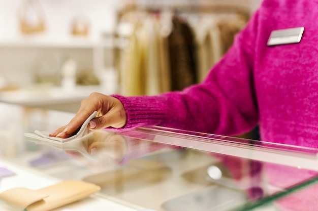 Gros plan du directeur des ventes essuyant le comptoir en verre dans la boutique préparant la boutique